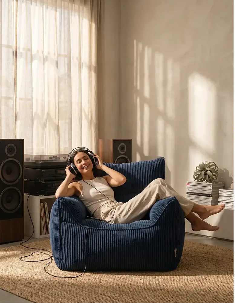 A model relaxing in a navy corduroy bean chair — lifestyle shot
