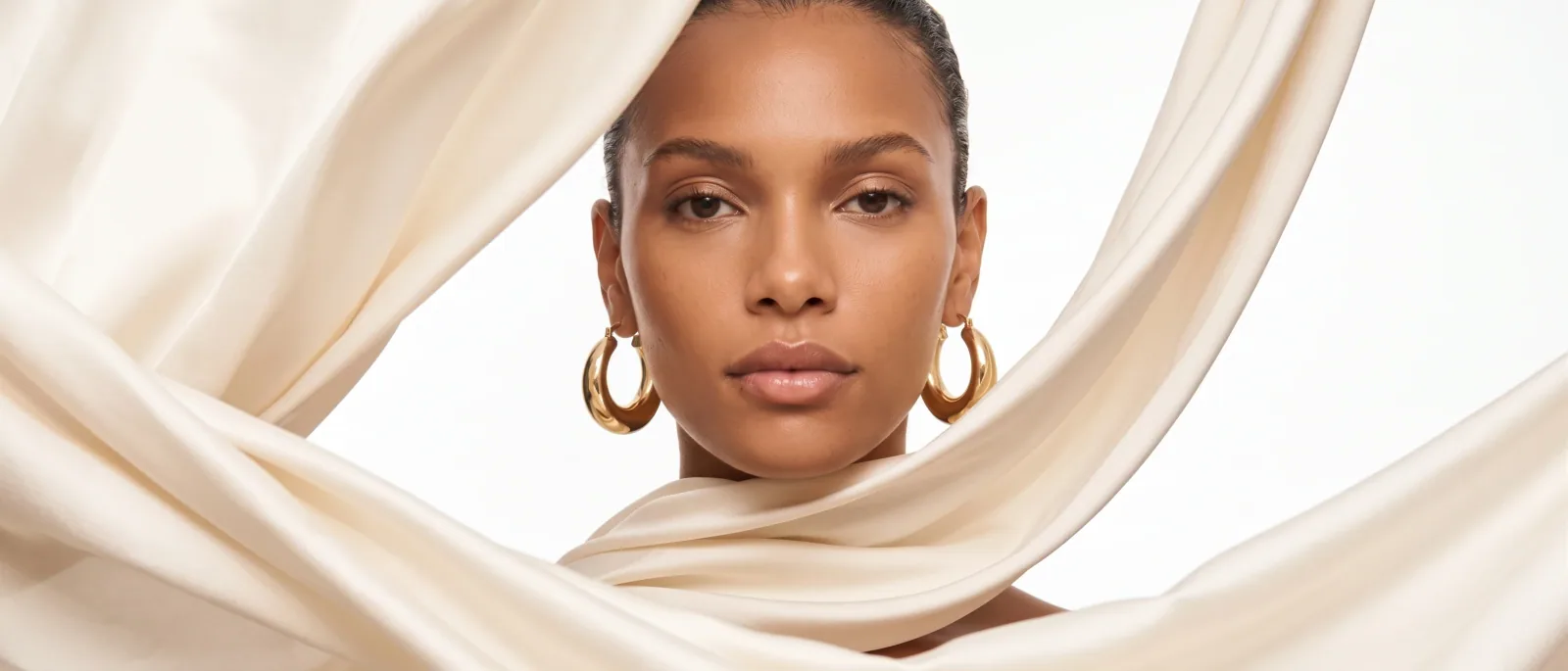 A model in an ivory silk scarf wearing gold hoop earrings — Epox on-model still