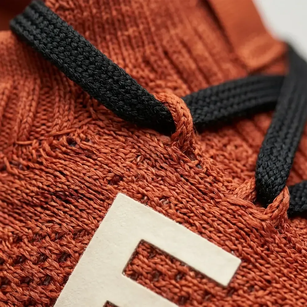 Rust knit running shoe — knit and lace close-up